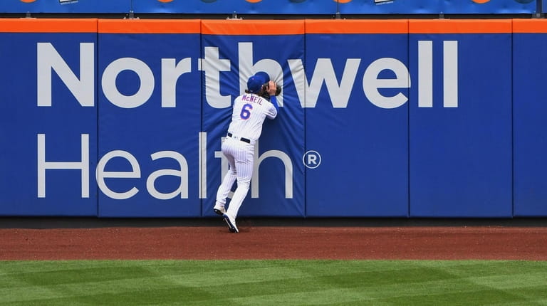 Mets leftfielder Jeff McNeil hits the wall after he leaps...