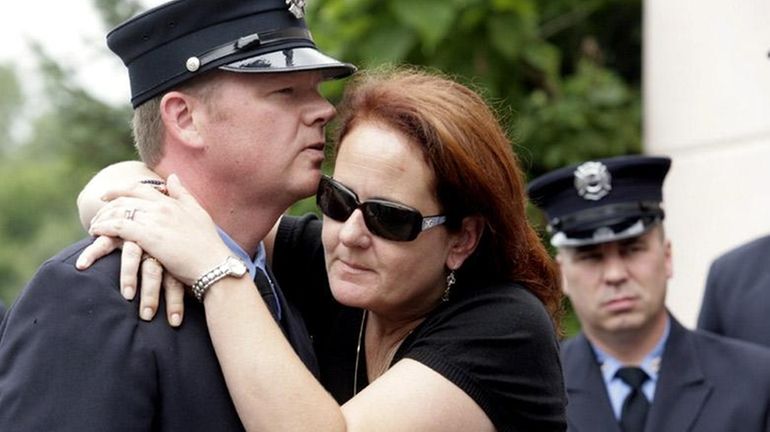 Jennifer McNamara, widow of 9/11 first responder John McNamara, hugs...