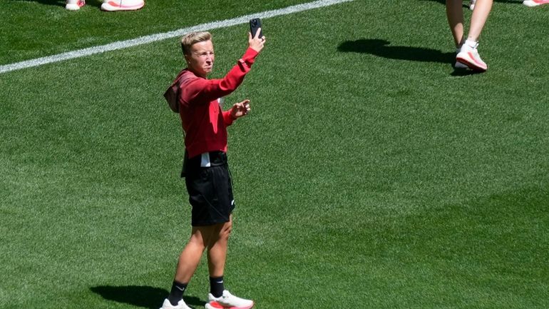 Coach Beverly Priestman of Canada takes photos on the pitch...