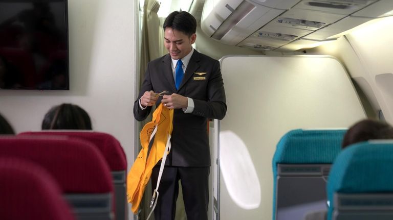 A flight attendant gives a pre-flight safety briefing to passengers. 