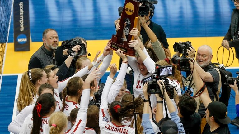 The Stanford women's volleyball team holds the championship trophy after...