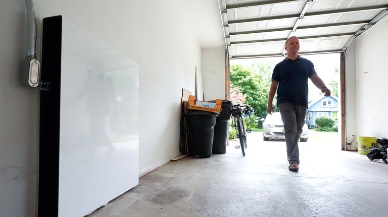 Jason Benedict walks into his garage near a Tesla Powerwall...