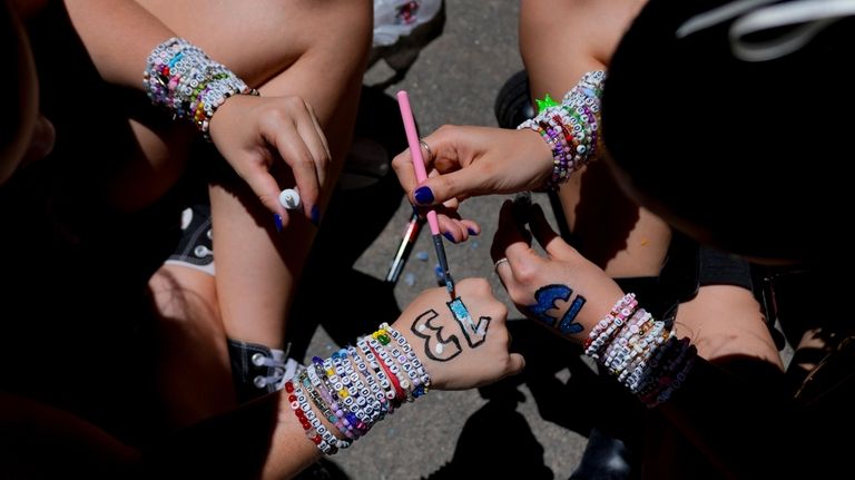 Fans of Taylor Swift paint their hands with the number...