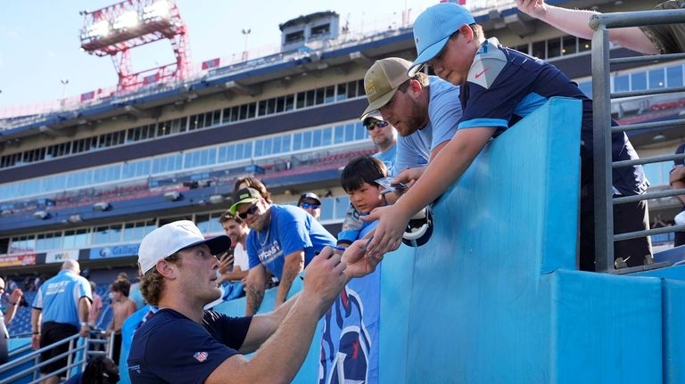 Tennessee Titans quarterback Will Levis, left, gives autographs before an...