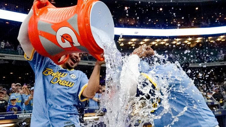 Milwaukee Brewers' Willy Adames douces Carlos Santana after a baseball...