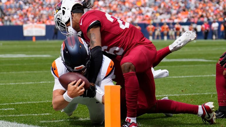 Denver Broncos quarterback Zach Wilson, left, gets tackled just short...