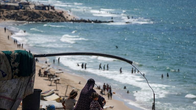 Displaced Palestinians sit next to their tent as they camp...