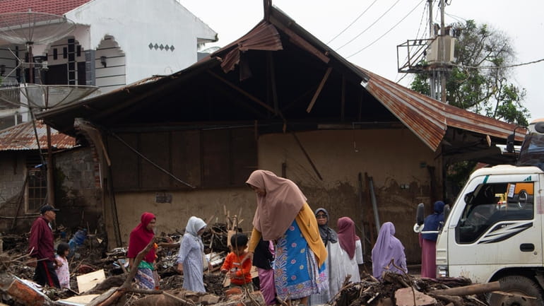 People inspect the damage by a flash flood in Tanah...