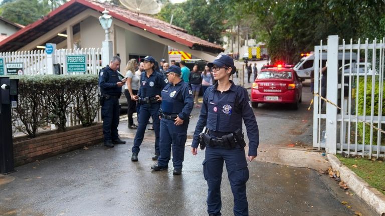 Police guard the gated community where a plane crashed in...