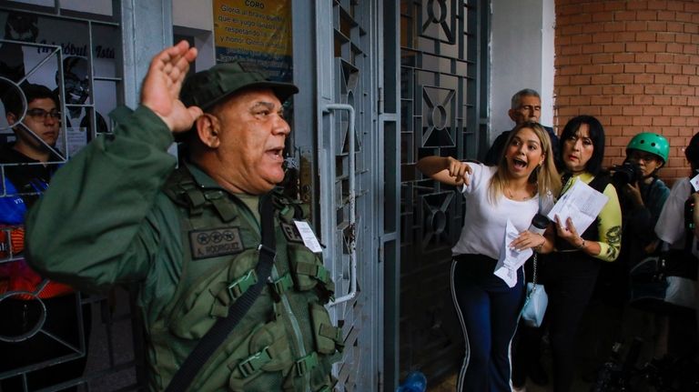 A National Guard officer addresses voters lining up at the...