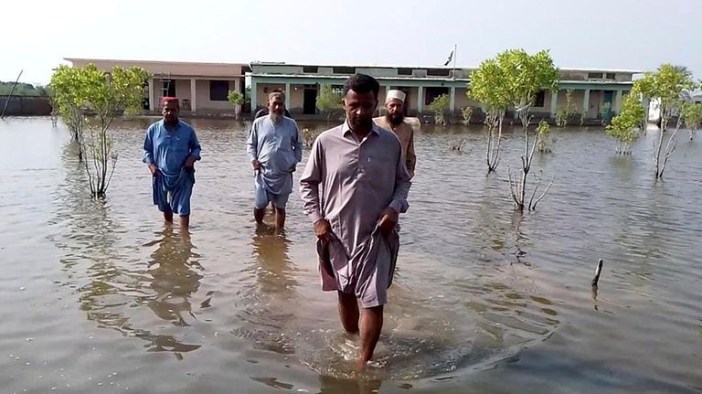 Villagers wade through flood area caused by heavy monsoon rains...