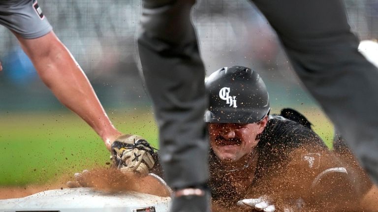 Chicago White Sox's Dominic Fletcher dives safely back to first...