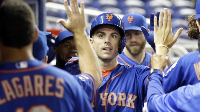 Mets' David Wright is congratulated in the dugout after scoring...