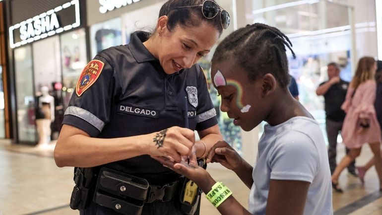 Officer Claudia Delgado paints the hand of 9-year-old Jacquera Charles on Tuesday...