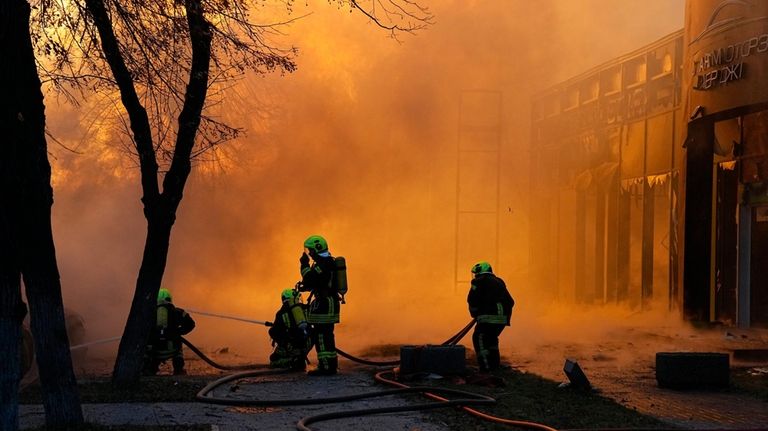 Firefighters work to extinguish a fire in a destroyed building...