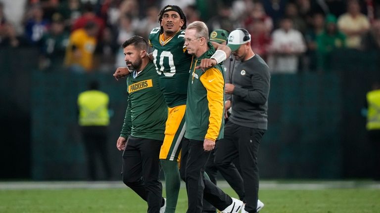 Green Bay Packers quarterback Jordan Love (10) is helped off...