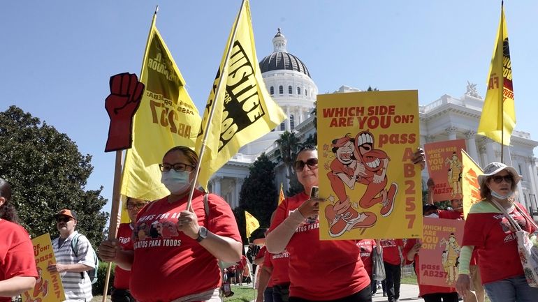 FILE -- Fast food workers and their supporters march past...