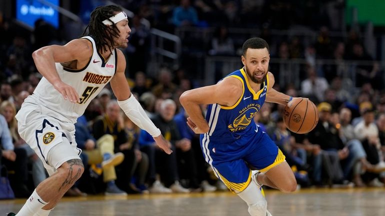 Golden State Warriors guard Stephen Curry, right, moves the ball...