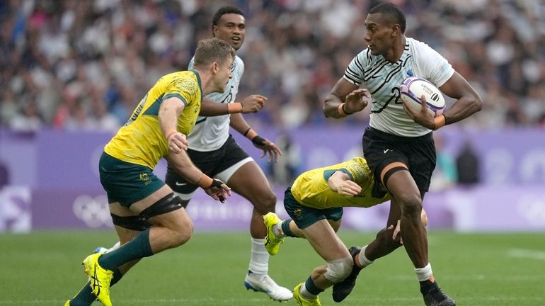 Fiji's Joseva Talacolo, right looks to fend off an incoming...