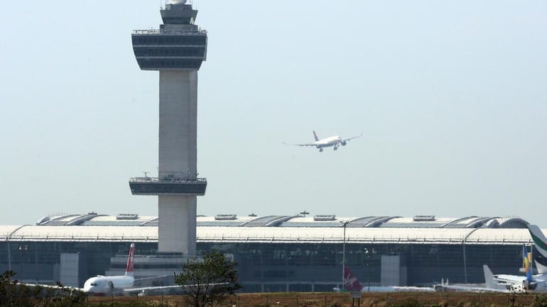 An aircraft flies past the control tower as it prepares...