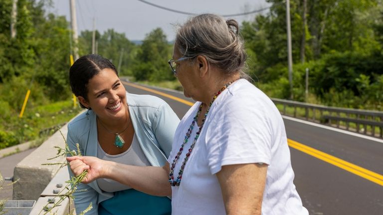 Jeanne Shanendoah holds out a plant to smell for Elizabeth...