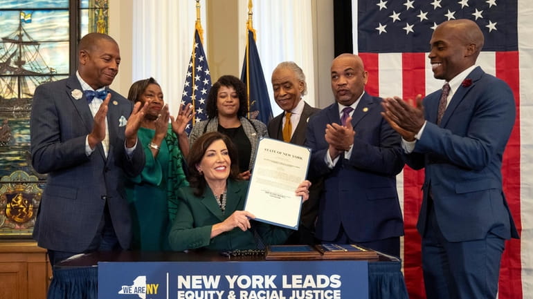 Political leaders applaud after Gov. Kathy Hochul signed a bill...