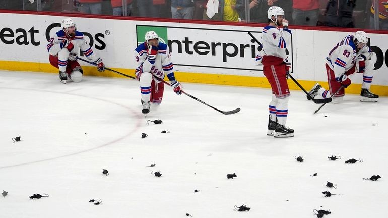 Rangers players remain on the plastic victory rat-littered ice after...