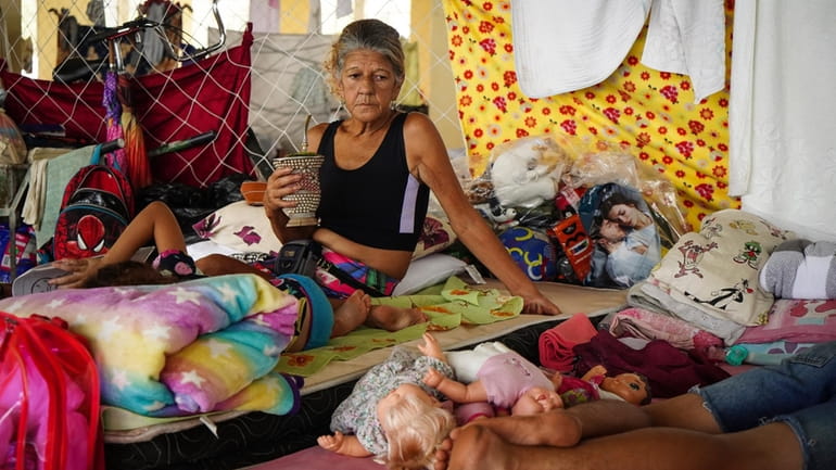Residents rest in a makeshift shelter for people whose homes...