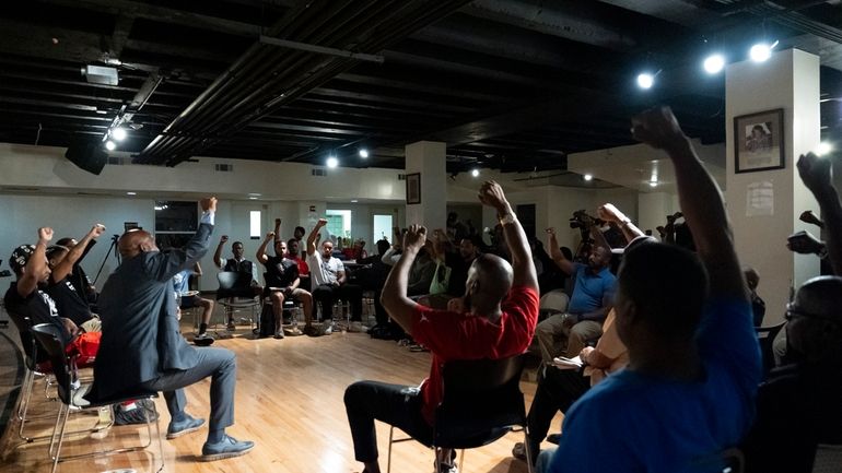 Panelists and attendees raise their fists during a Black Man...