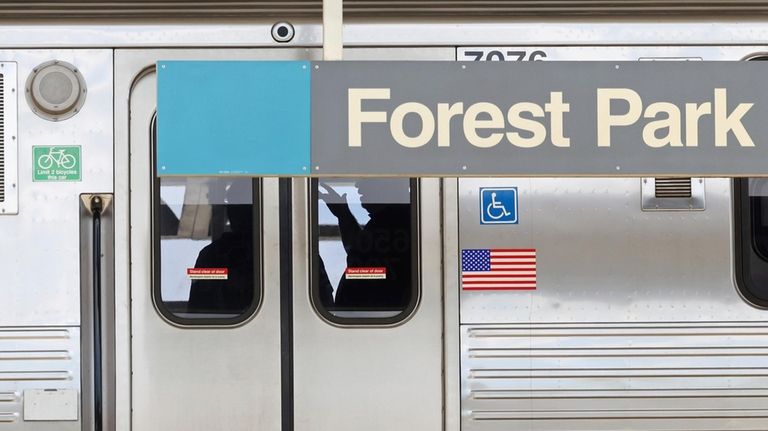 Police investigators work inside a CTA Blue Line train parked...