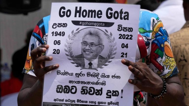 FILE -A protestor holds a poster designed as a death...