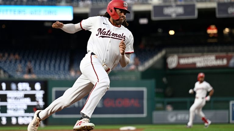 Washington Nationals' James Wood, foreground, rounds third base to score...