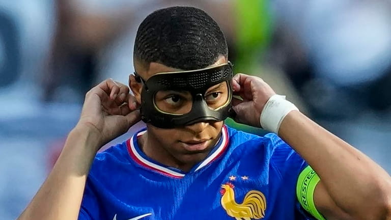 Kylian Mbappe of France adjusts his mask after scoring a...