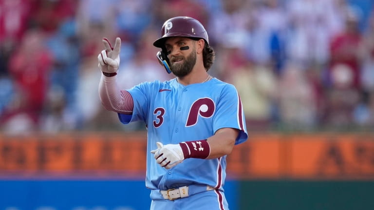Philadelphia Phillies' Bryce Harper reacts after hitting a run-scoring double...