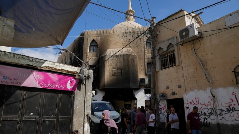 Palestinians stand outside a damaged mosque following an Israeli military...