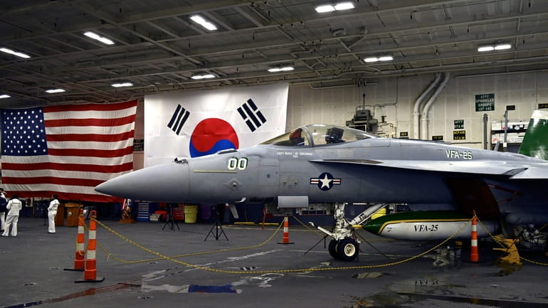 An F-18 fighter aircraft sits in the hanger of the...