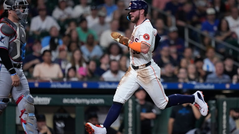 Houston Astros' Trey Cabbage scores on a ground out by...