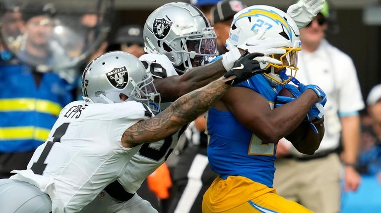 Los Angeles Chargers running back J.K. Dobbins, right, runs against...