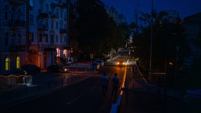 People walk along a road during a blackout in central...