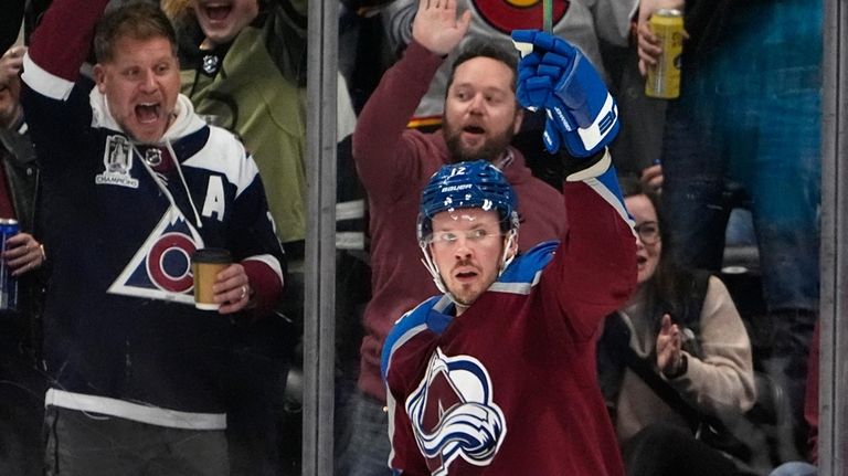 Colorado Avalanche center Ryan Johansen raises his stick after scoring...