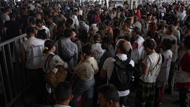 Palestinians and foreign aid workers wait to cross into Egypt...