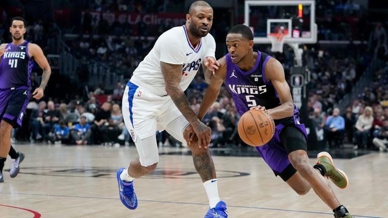 Sacramento Kings guard De'Aaron Fox, right, drives against Los Angeles...