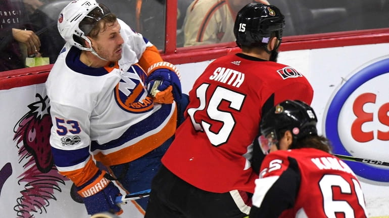 Islanders' Casey Cizikas is checked into the boards by Ottawa...