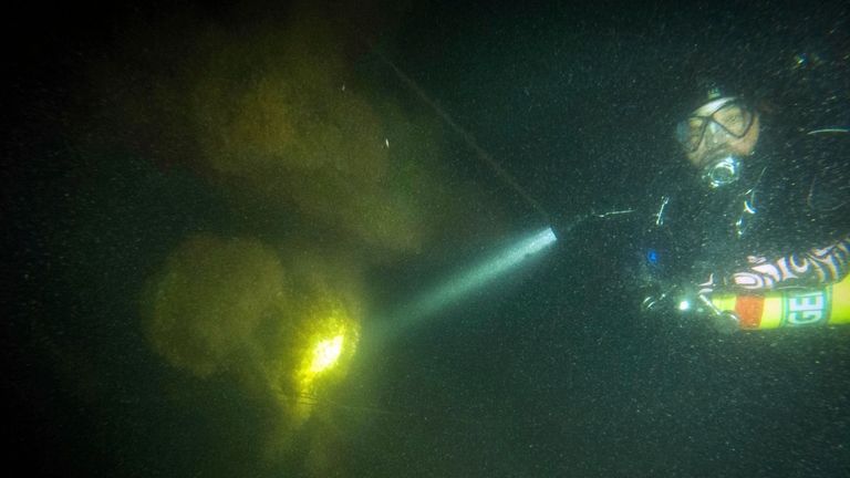 Diver Steve Abbate inspects a propeller on the Defender submarine...