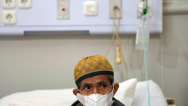 Misnar, a street vendor who suffers from pneumonia, sits on...