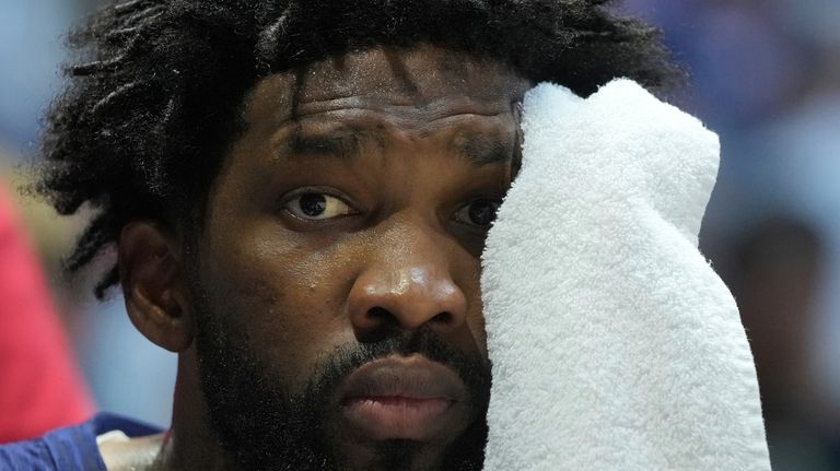 United States' center Joel Embiid wipes his face with a...