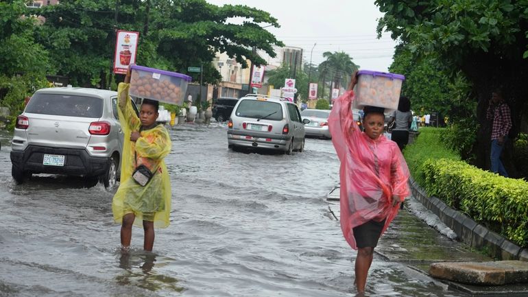 Women walk along a flooded street after a heavy downpour...