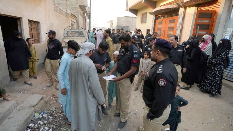 A Police officer checks documents of a resident during a...