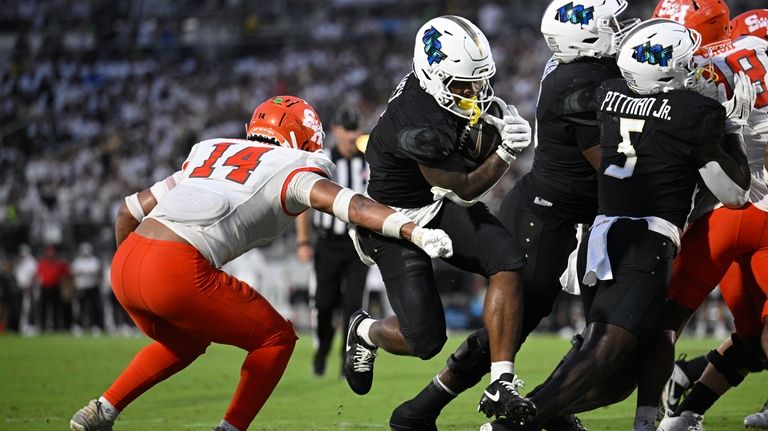 Central Florida running back RJ Harvey, center, leaps over the...