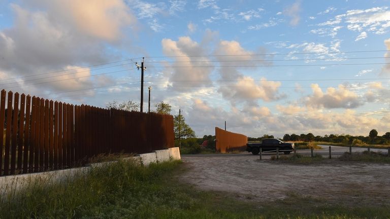 A truck passes through a section of border fence in...